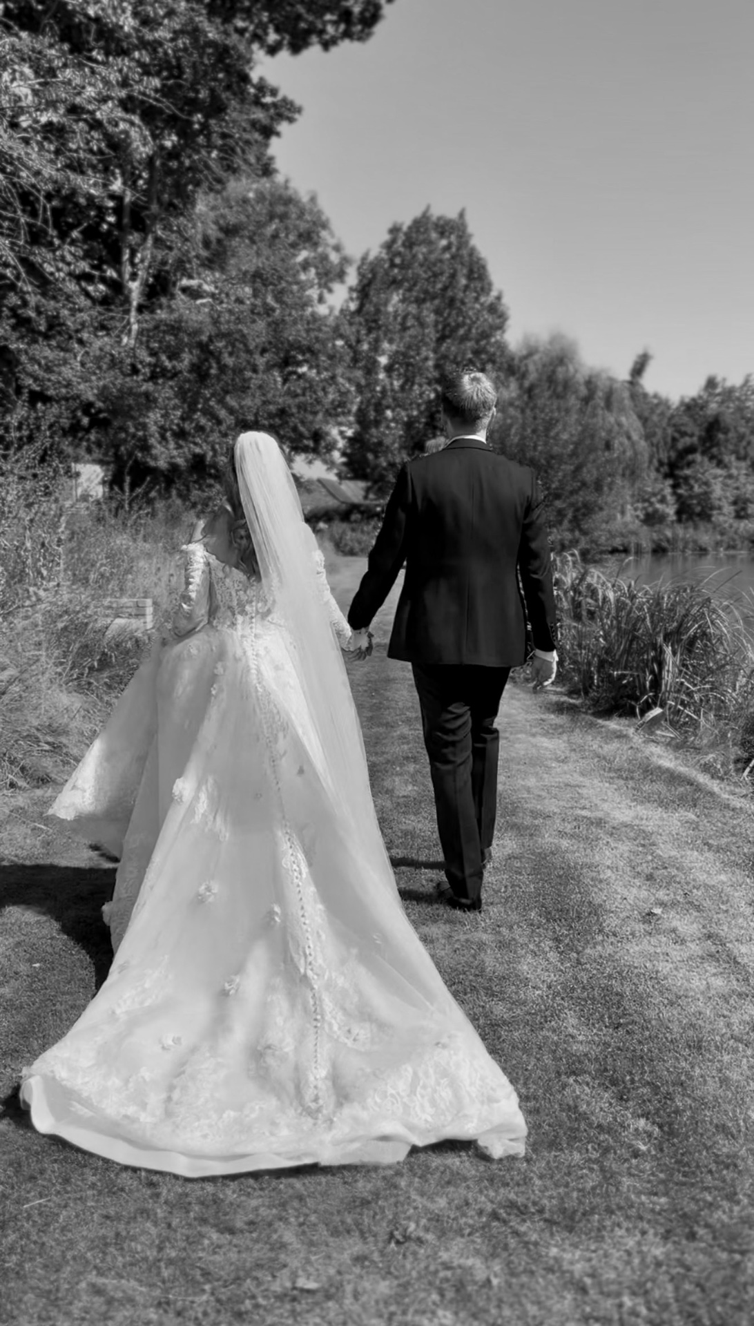 Couple walking away with a lake and trees in the background