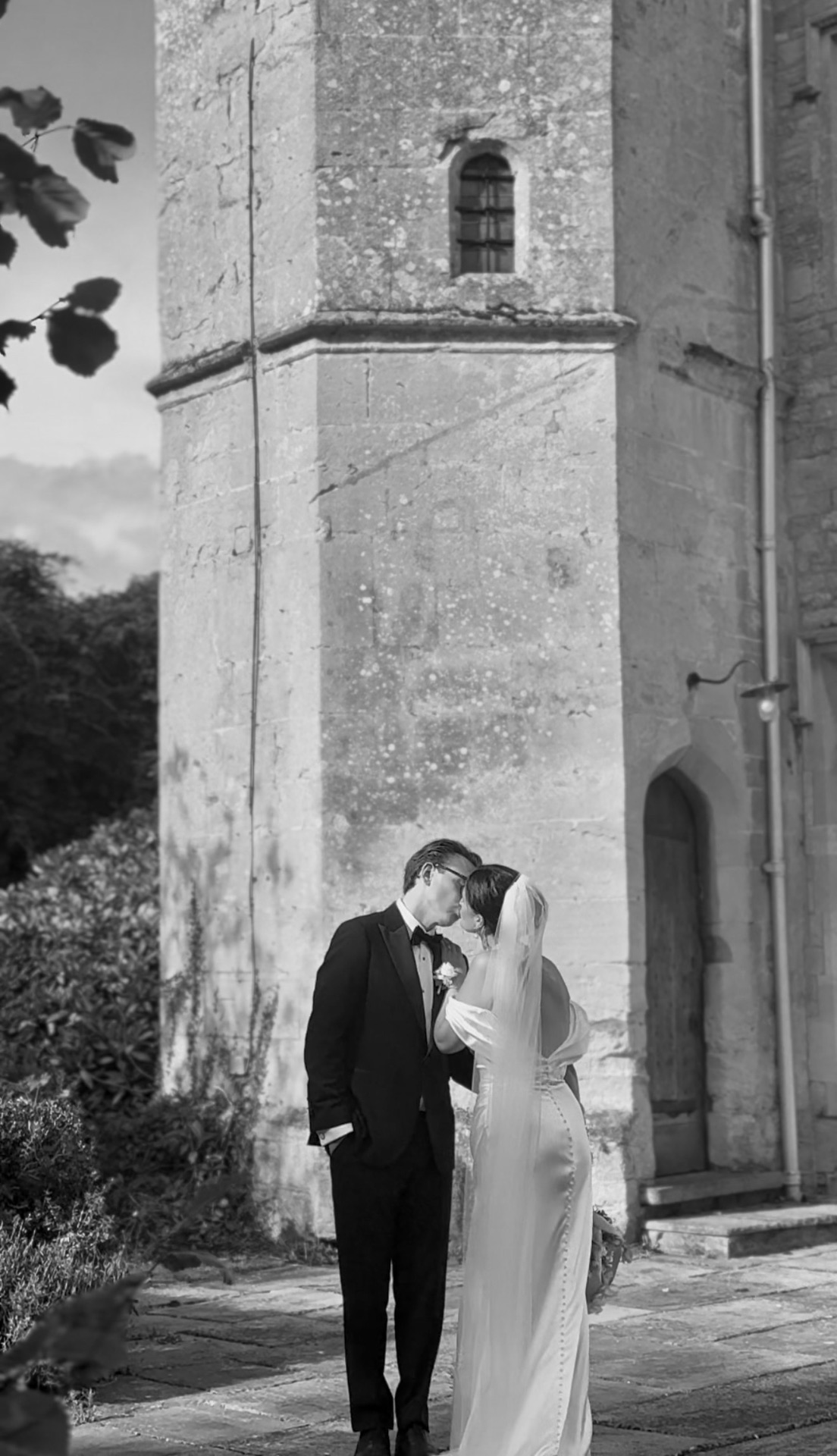 Bride and groom kissing in front of a stone tower